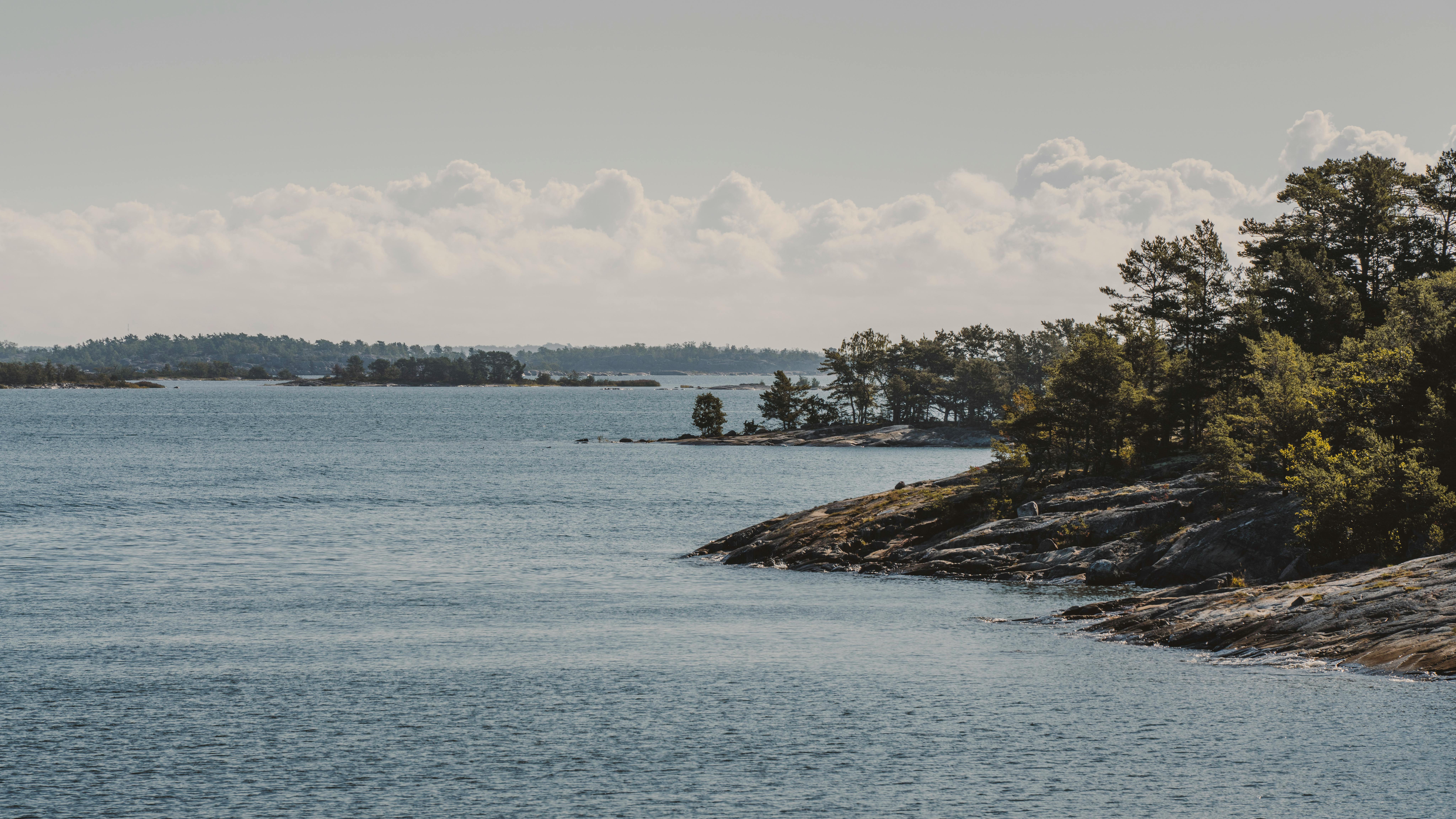 Explore Helsinki’s nearby islands like a local Scenic view of Helsinki’s archipelago with rocky shores and green islands on a summer day.